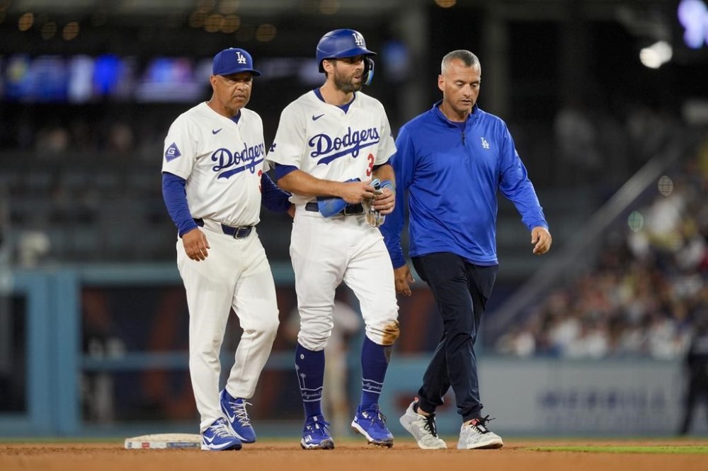 Los Angeles Dodgers' Chris Taylor, center, walks off the field with manager Dave Roberts, left, during the seventh inning of a baseball game against the San Francisco Giants, Wednesday, July 24, 2024, in Los Angeles. (AP Photo/Ryan Sun)