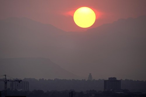 The sun sets behind the mountains obscured by wildfire smoke from blazes in the American West and provinces of western Canada late Wednesday, July 24, 2024, in Denver. (AP Photo/David Zalubowski)