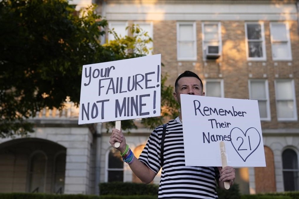 James Alvarado holds signs outside of the Uvalde County Courthouse as he shows his support for the families and victims of the shootings at Robbs Elementary School, Thursday, July 25, 2024, in Uvalde, Texas. Former Uvalde Consolidated Independent School District police officer Adrian Gonzales made his first court appearance on charges of abandoning and failing to protect children. (AP Photo/Eric Gay)