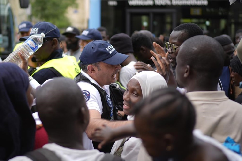 City officials try to maintain calm during a migrants' protest at the 2024 Summer Olympics, Thursday, July 25, 2024, in Paris, France. On the eve of the grandiose opening ceremony for the Paris Olympics, police cleared out migrants sleeping in a tent camp in the capital as social and environmental advocacy groups raise attention to criticisms of the Paris Games such as the displacement of migrants and housing issues. (AP Photo/David Goldman)