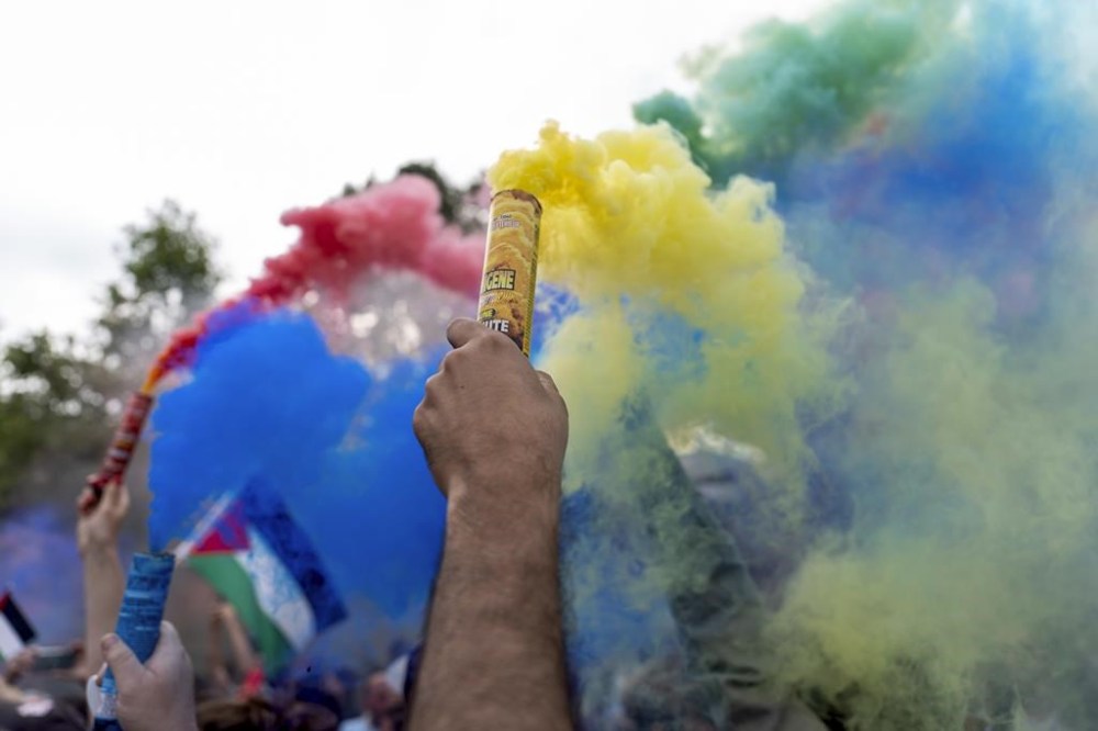 Protesters release smoke in the colors of the Olympic rings during a demonstration by several associations for what they called the