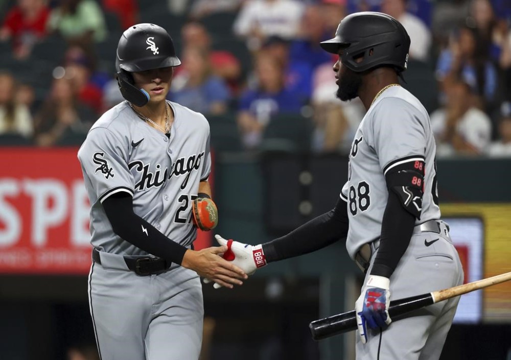 Chicago White Sox Brooks Baldwin (27) slaps hands with Luis Robert Jr. (88) after scoring against the Texas Rangers in the third inning of a baseball game Thursday, July 25, 2024, in Arlington, Texas. (AP Photo/Richard W. Rodriguez)