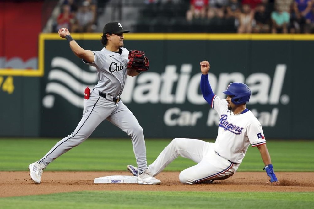 Chicago White Sox second baseman Nicky Lopez (8) forces out Texas Rangers' Marcus Semien (2) as he throws to first for the double play the first inning of a baseball game Thursday, July 25, 2024, in Arlington, Texas. (AP Photo/Richard W. Rodriguez)