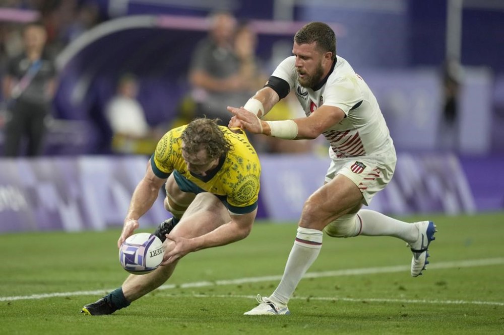 Australia's Henry Hutchison, has his shirt grabbed by United States' Steve Tomasin during the men's quarterfinal match Rugby Sevens between Australia and the United States at the 2024 Summer Olympics, in the Stade de France, Thursday, July 25, 2024, in Saint-Denis, France. (AP Photo/Tsvangirayi Mukwazhi)