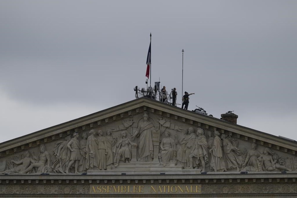 Security staff stand atop the roof of the National Assembly in Paris, France, ahead of the opening ceremony of the 2024 Summer Olympics, Friday, July 26, 2024. (AP Photo/Charlie Riedel)