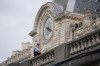 A police officer stands watch near the Musée d'Orsay as the city prepares for the start of the opening ceremony in Paris, France, before the the 2024 Summer Olympics, Friday, July 26, 2024. (AP Photo/Rebecca Blackwell)