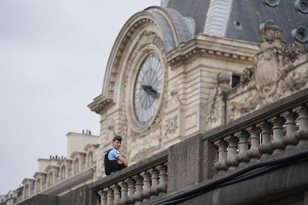 A police officer stands watch near the Musée d'Orsay as the city prepares for the start of the opening ceremony in Paris, France, before the the 2024 Summer Olympics, Friday, July 26, 2024. (AP Photo/Rebecca Blackwell)