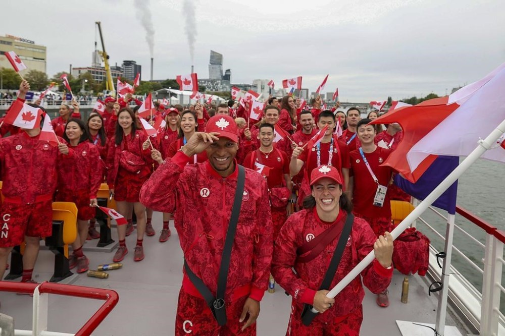 Canada's flag-bearers Maude Charron, right, and Andre de Grasse, left, pose for photos on a boat with their team before the start of the opening ceremony for the 2024 Summer Olympics on the Seine River in Paris, France, Friday, July 26, 2024. THE CANADIAN PRESS/AP-Cao Can/Pool Photo via AP