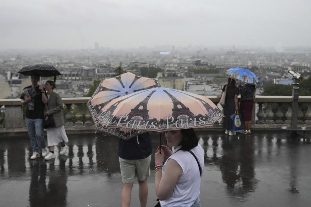 People in the Montmartre district use umbrellas to protect from the rain in Paris, France, during the opening ceremony of the 2024 Summer Olympics, Friday, July 26, 2024. (AP Photo/Dita Alangkara)