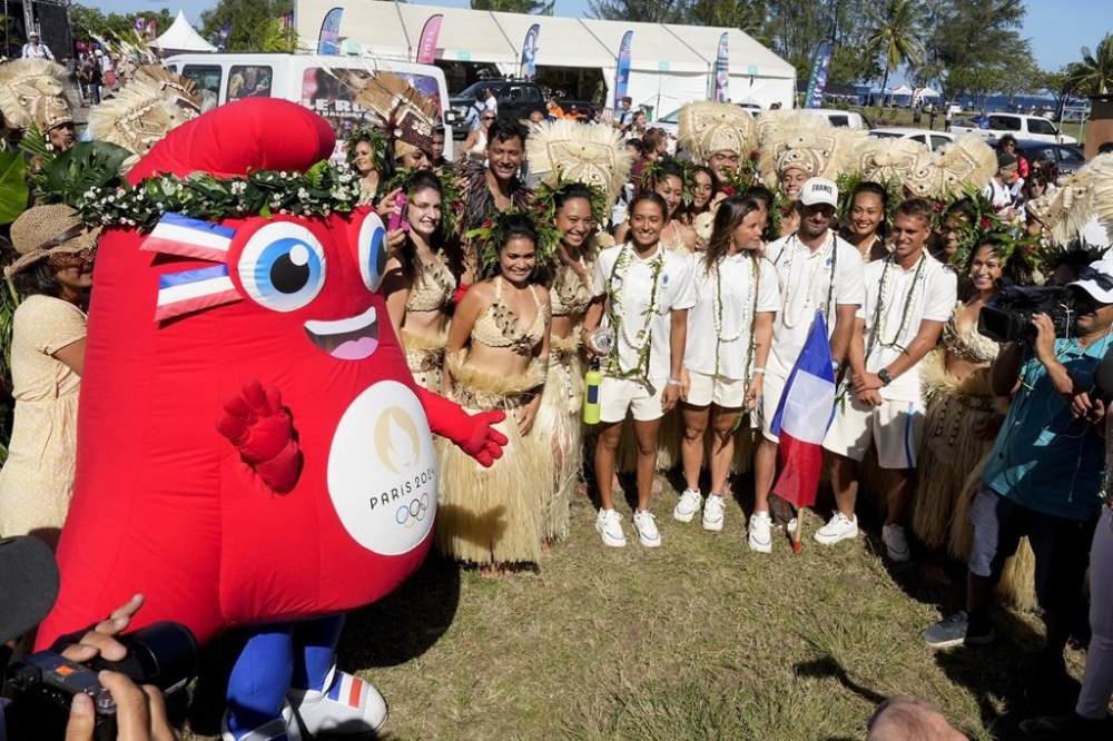 The surfing team from France stand with dancers and the mascot during an opening ceremony for the 2024 Summer Olympics surfing competition Friday, July 26, 2024, in Papara, Tahiti. (AP Photo/Gregory Bull)
