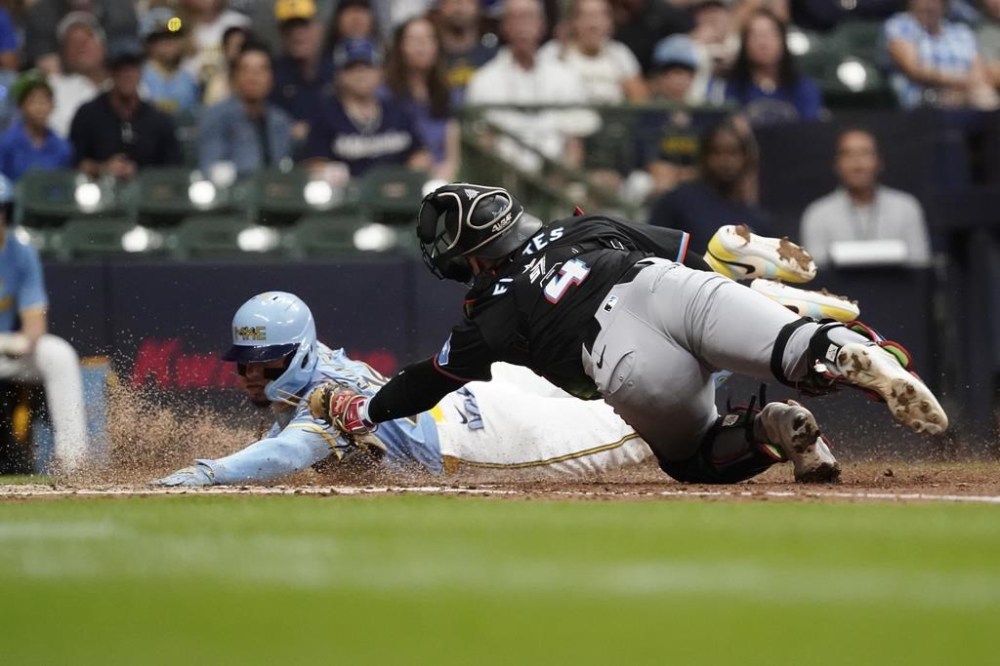 Milwaukee Brewers' William Contreras, left, slides safely into home past the tag of Miami Marlins' Nick Fortes, right, to score on a sacrifice fly hit by Gary Sánchez during the fourth inning of a baseball game Friday, July 26, 2024, in Milwaukee. (AP Photo/Aaron Gash)