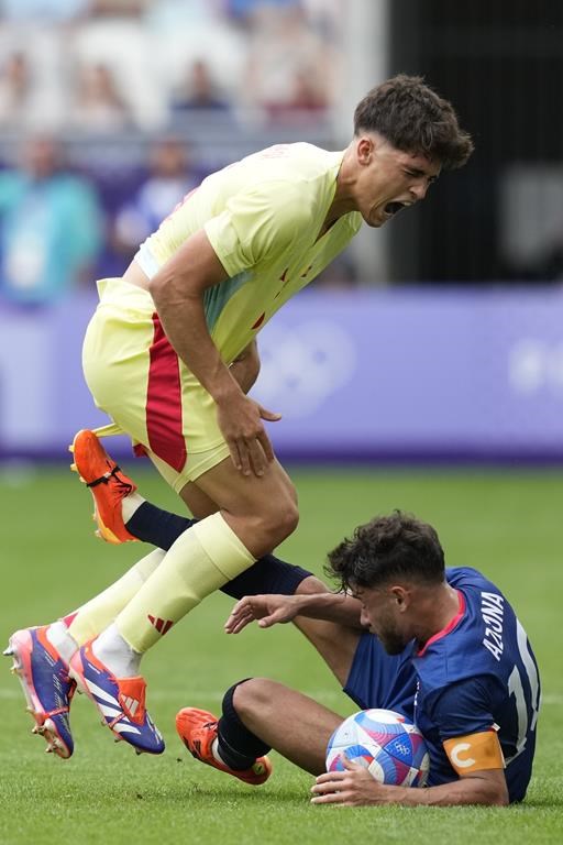 Spain'sPau Cubarsi, left, is fouled by Dominican Republic's Edison Azcona during the men's Group C soccer match at the Bordeaux stadium at the 2024 Summer Olympics, Saturday, July 27, 2024, in Bordeaux, France. (AP Photo/Moises Castillo)