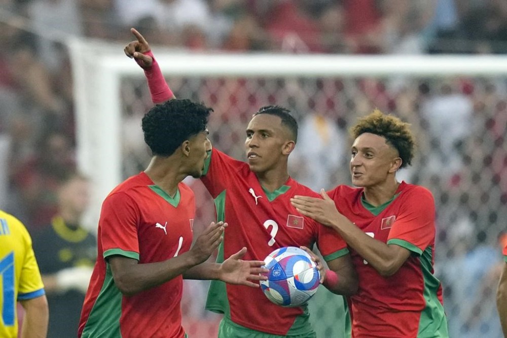 Morocco's Soufiane Rahimi, center, celebrates with teammates after scoring his side's first goal from the penalty spot during the men's Group B soccer match between Morocco and Ukraine at Geoffroy-Guichard stadium during the 2024 Summer Olympics, Saturday, July 27, 2024, in Saint-Etienne, France. (AP Photo/Silvia Izquierdo)