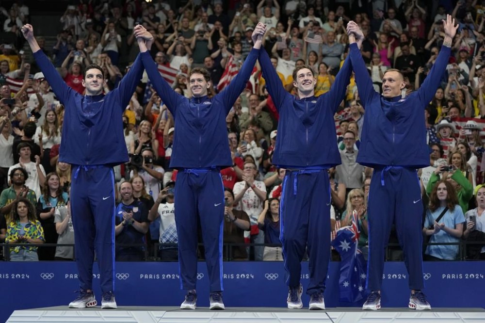 The United States men's 4x100-meter freestyle relay team celebrates on the podium after winning the gold medal at the 2024 Summer Olympics, Saturday, July 27, 2024, in Nanterre, France. (AP Photo/Matthias Schrader)