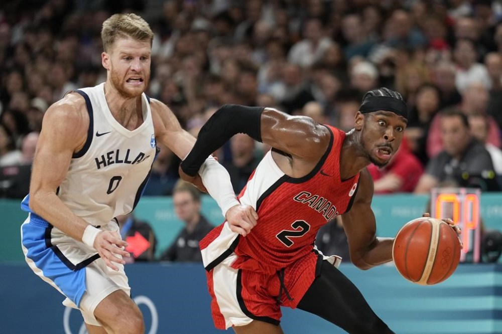 Shai Gilgeous-Alexander, of Canada, drives past Thomas Walkup, of Greece, in a men's basketball game at the 2024 Summer Olympics, Saturday, July 27, 2024 in Villeneuve-d'Ascq, France. (AP Photo/Mark J. Terrill)