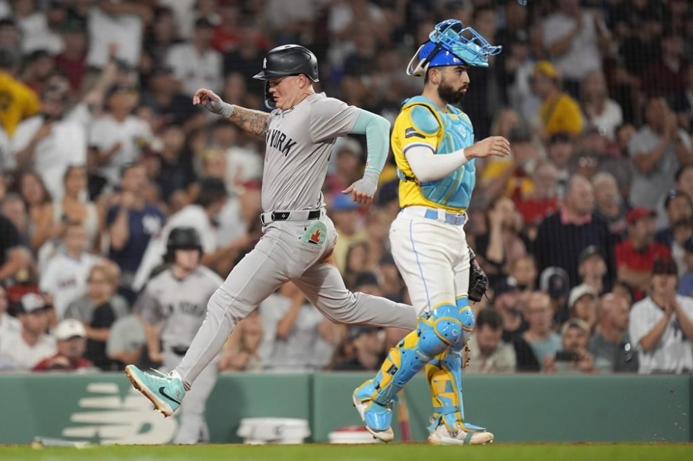 New York Yankees' Alex Verdugo scores against Boston Red Sox catcher Connor Wong, right, on a single by Aaron Judge during the fifth inning of a baseball game, Saturday, July 27, 2024, in Boston. (AP Photo/Michael Dwyer)