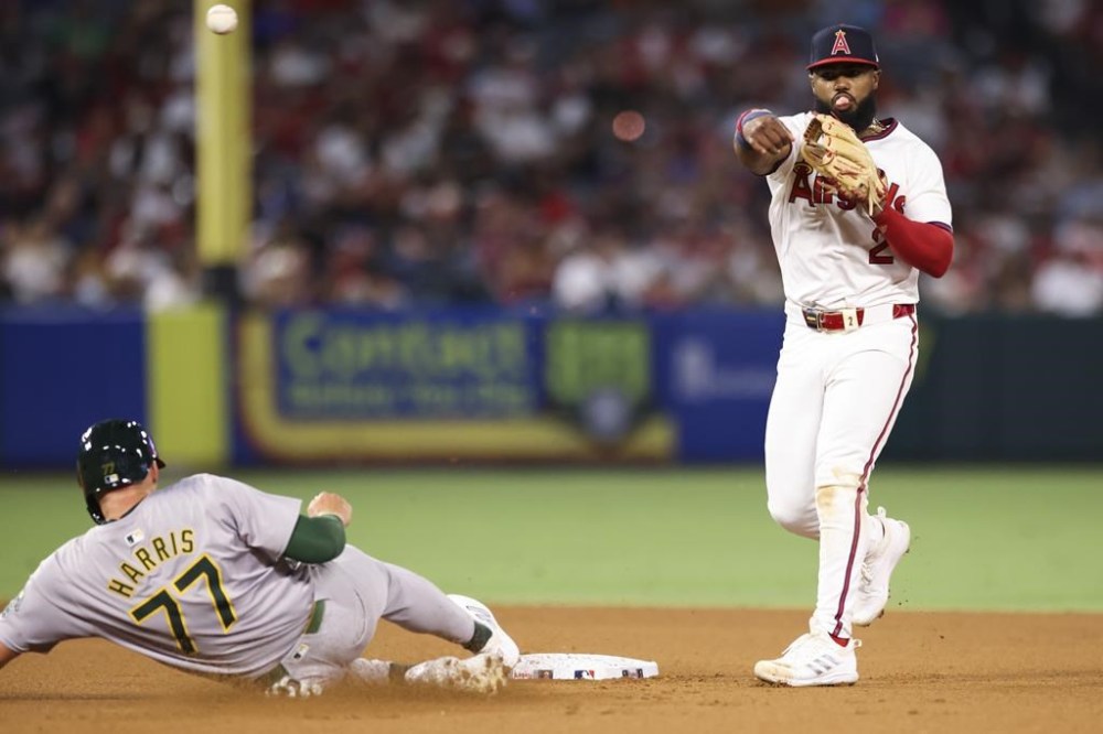 Los Angeles Angels third baseman Luis Rengifo (2) throws to first base to complete a double play as Oakland Athletics' Brett Harris (77) slides into second base during seventh inning of a baseball game in Anaheim, Calif., Saturday, July 27, 2024. (AP Photo/Jessie Alcheh)