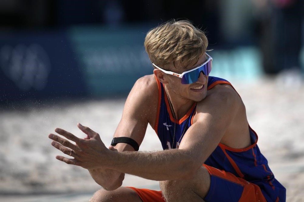 Steven van de Velde of the Netherlands grimaces and wipes his hands during the beach volleyball match between the Netherlands and Italy at Eiffel Tower Stadium at the 2024 Summer Olympics in Paris, France, Sunday, July 28, 2024. (AP Photo/Louise Delmotte)