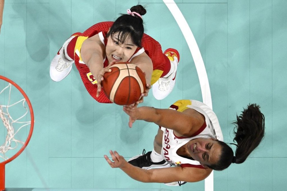 Yueru Li, of China, and Maite Cazorla, of Spain, reach for a rebound in a women's basketball game at the 2024 Summer Olympics, Sunday, July 28, 2024, in Villeneuve-d'Ascq, France. (Sameer Al-Doumy/Pool Photo via AP)