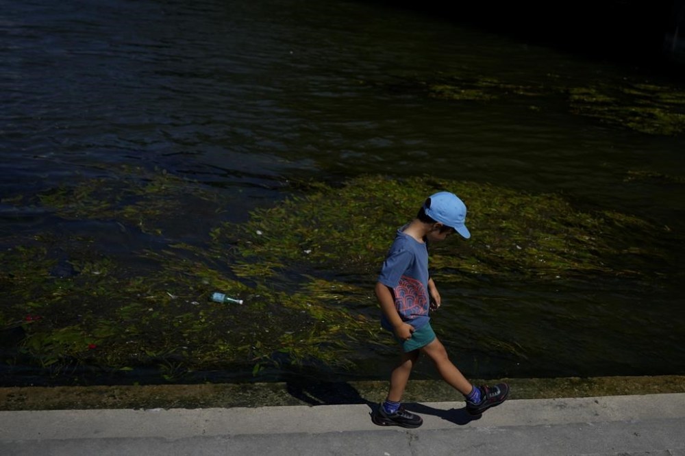 A child walks along the Seine river at the 2024 Summer Olympics, Sunday, July 28, 2024, in Paris, France. (AP Photo/Natacha Pisarenko)