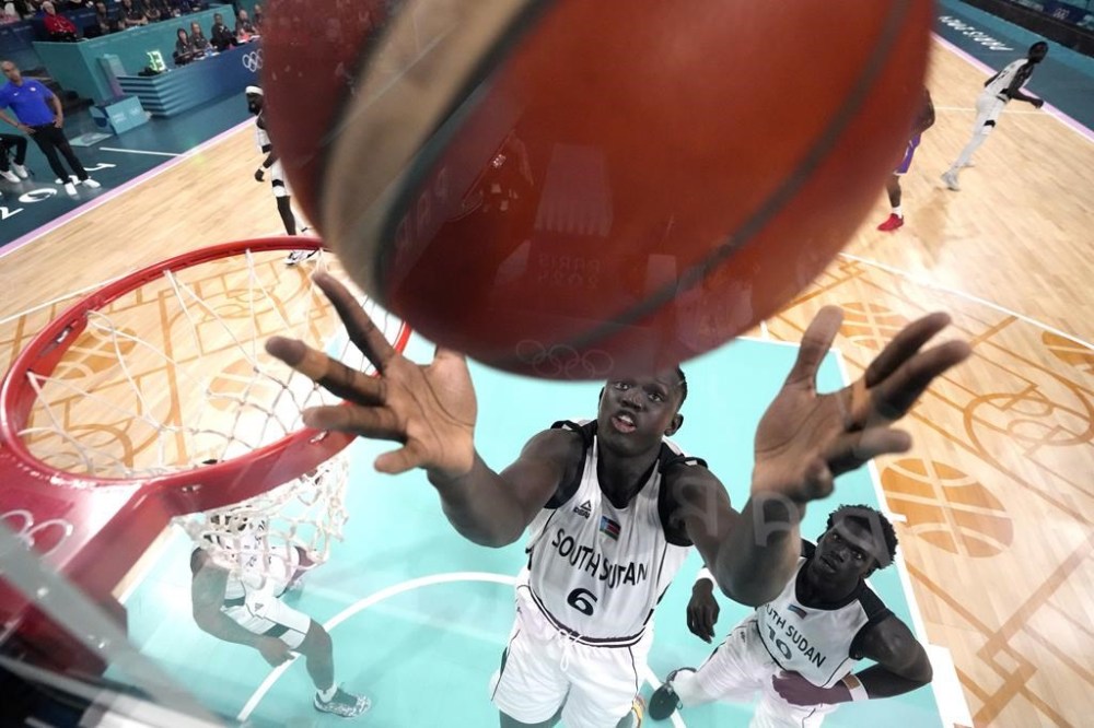 Khaman Maluach, of South Sudan, reaches for a rebound in a men's basketball game against Puerto Rico at the 2024 Summer Olympics, Sunday, July 28, 2024, in Villeneuve-d'Ascq, France. (AP Photo/Michael Conroy, Pool)