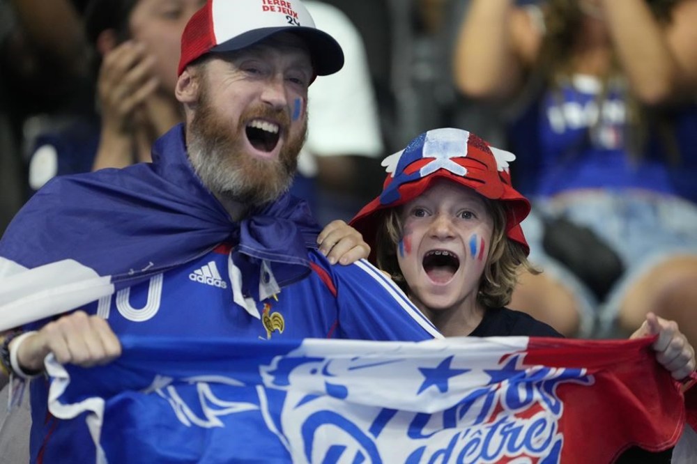 Supporters of Leon Marchand, of France, react after he won the men's 400-meter individual medley final at the 2024 Summer Olympics, Sunday, July 28, 2024, in Nanterre, France. (AP Photo/Matthias Schrader)