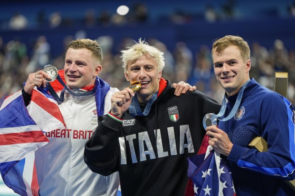 Gold medalist, Nicolo Martinenghi, center, of Italy, poses with silver medalists, Nic Fink, right, of the the United States, and Adam Peaty, of Britain, after the men's 100-meter breaststroke final at the 2024 Summer Olympics, Sunday, July 28, 2024, in Nanterre, France. (AP Photo/Martin Meissner)