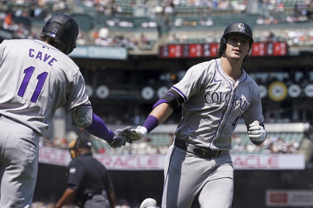 Colorado Rockies' Michael Toglia (4) celebrates with Jake Cave (11) after hitting a solo home run againsr the San Francisco Giants in the seventh inning of a baseball game in San Francisco, Sunday, July 28, 2024. (AP Photo/Kavin Mistry)