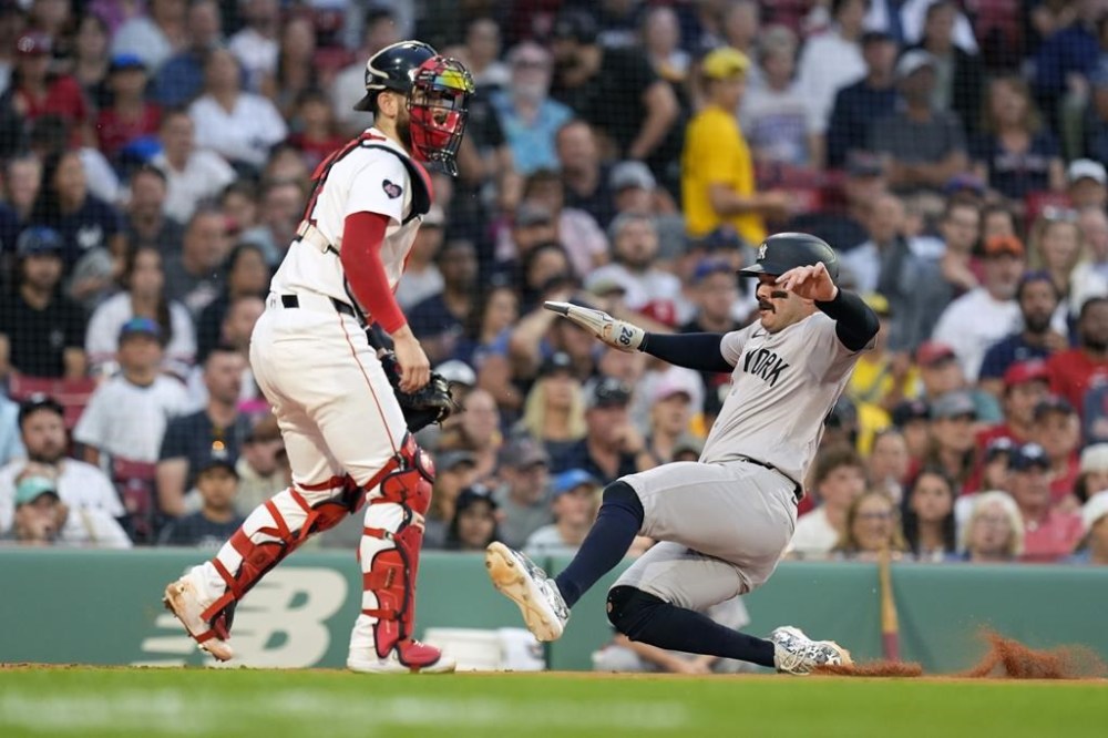 New York Yankees' Austin Wells, right, scores in front of Boston Red Sox catcher Connor Wong, left, on a two-run single by Gleyber Torres during the first inning of a baseball game, Sunday, July 28, 2024, in Boston. (AP Photo/Michael Dwyer)