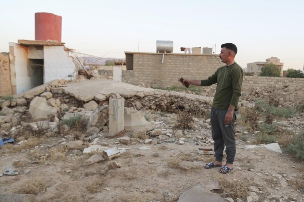 Hadi Shammo, 30, a Yazidi returnee, stands amid the wreckage of his destroyed family house in the village of Dugure in Sinjar, Iraq, Tuesday, July 16, 2024.