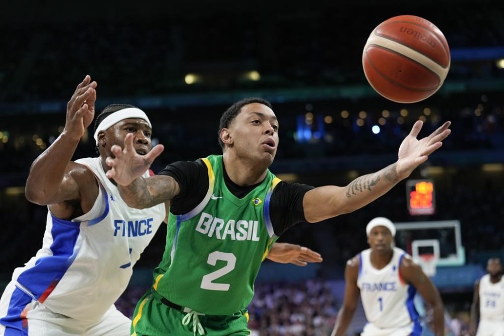 Yago Santos, of Brazil, reaches for the ball in front of Guerschon Yabusele, of France, in a men's basketball game at the 2024 Summer Olympics, Saturday, July 27, 2024 in Villeneuve-d'Ascq, France. (AP Photo/Mark J. Terrill)