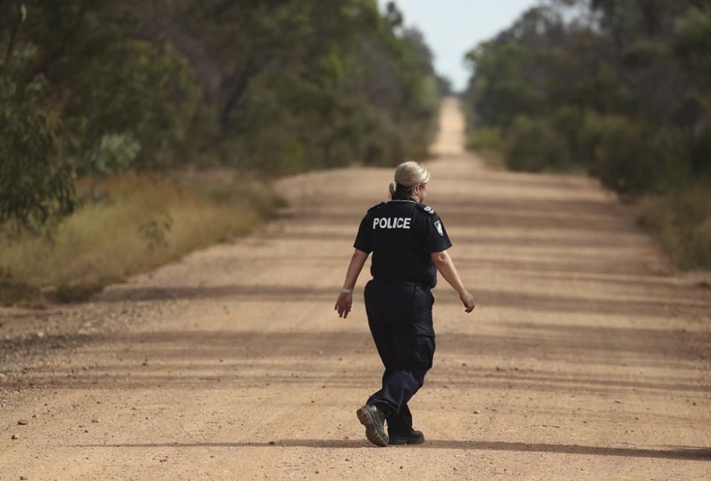 A Police officers walks across a road near the scene of a fatal shooting in Wieambilla, Australia, Dec. 13, 2022. Three Christian extremists who killed two police officers, a bystander and wounded a third police officer in an ambush on a rural Australian property in 2022 had been bent on intimidating state authorities, a coroner was told on Monday, July 29, 2024. (Jason O'Brien/AAP Image via AP)