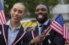 Noah Lyles, right, of the United States poses for photos while traveling along the Seine River in Paris, France, during the opening ceremony of the 2024 Summer Olympics, Friday, July 26, 2024. (AP Photo/Ashley Landis,Pool)