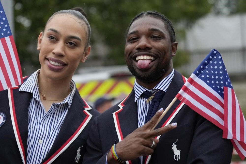 Noah Lyles, right, of the United States poses for photos while traveling along the Seine River in Paris, France, during the opening ceremony of the 2024 Summer Olympics, Friday, July 26, 2024. (AP Photo/Ashley Landis,Pool)