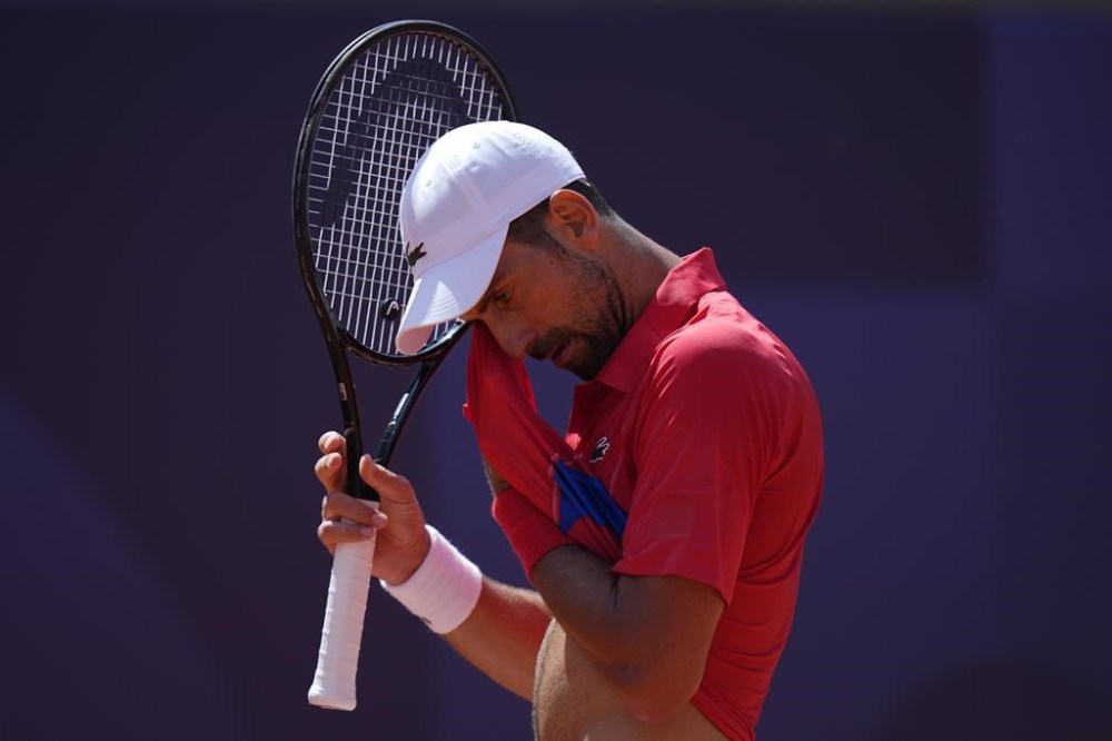 Serbia's Novak Djokovic wipes his face as he plays Spain's Rafael Nadal during their men's singles second round match at the 2024 Summer Olympics, Monday, July 29, 2024, at the Roland Garros stadium in Paris, France. (AP Photo/Andy Wong)