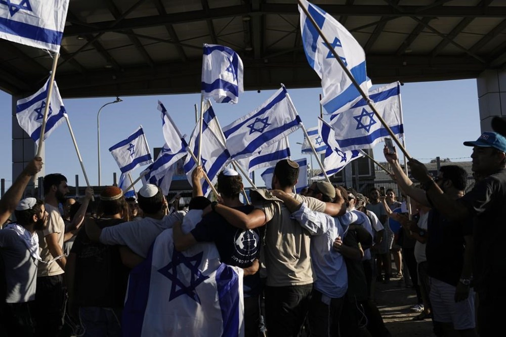 Protesters wave Israeli national flags in support of soldiers being questioned for detainee abuse, outside of the Sde Teiman military base, Monday, July 29, 2024. The Israeli military said Monday it was holding nine soldiers for questioning following allegations of