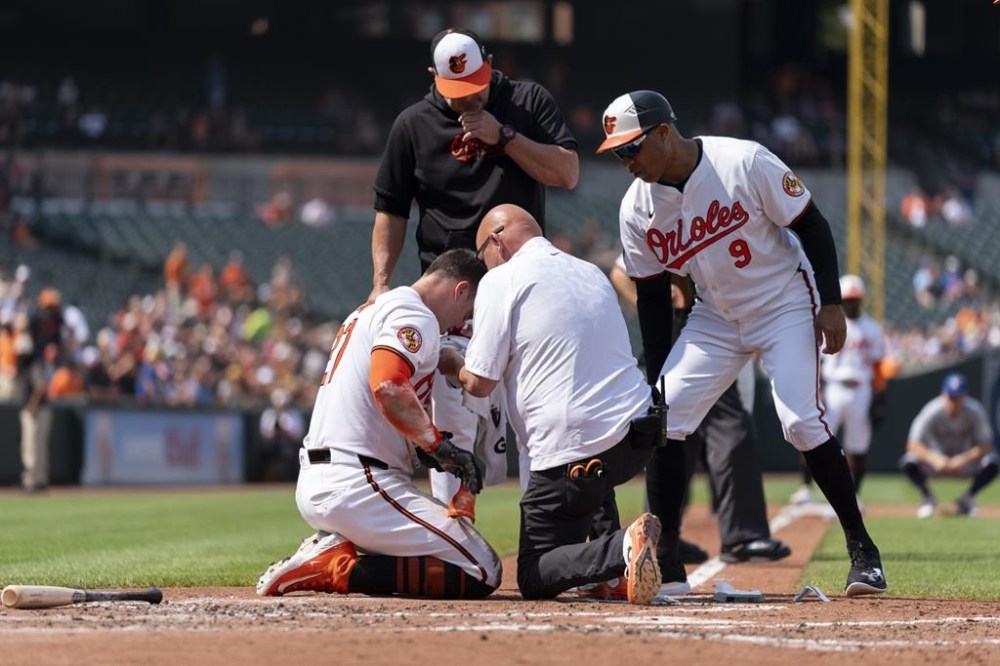 A trainer and coaches attend to Baltimore Orioles' James McCann after he was hit by a pitch by Toronto Blue Jays starting pitcher Yariel Rodriguez during the first inning in the first baseball game of a doubleheader, Monday, July 29, 2024, in Baltimore. (AP Photo/Stephanie Scarbrough)