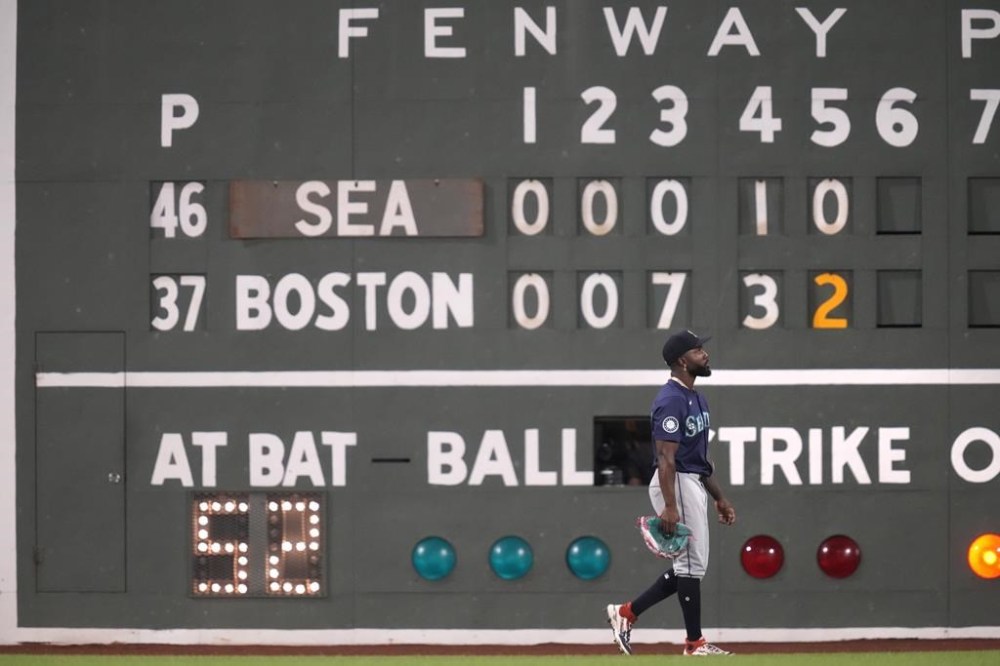 Seattle Mariners left fielder Randy Arozarena walks past the Green Monster scoreboard during the fifth inning of a baseball game against the Boston Red Sox, Monday, July 29, 2024, in Boston. (AP Photo/Charles Krupa)