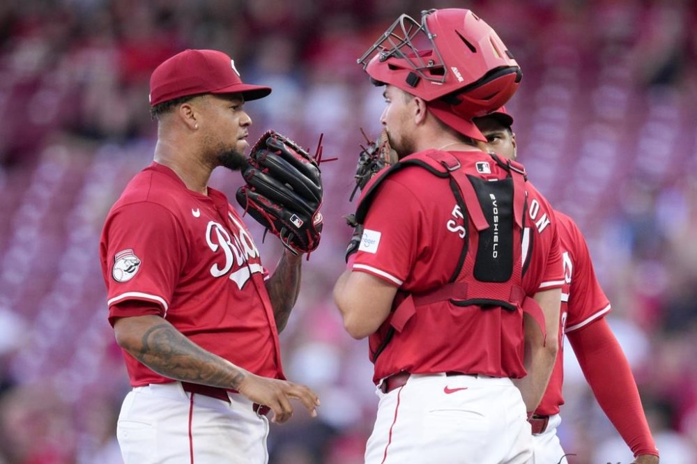 Cincinnati Reds' Frankie Montas, left, speaks with teammate Tyler Stephenson during the third inning of a baseball game against the Colorado Rockies, Wednesday, July 10, 2024, in Cincinnati. (AP Photo/Jeff Dean)