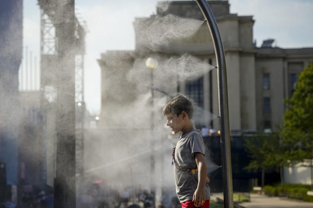 Eli, 10, cools off under a misting fountain on a hot afternoon during the 2024 Summer Olympics, Monday, July 29, 2024, in Paris, France. (AP Photo/Vadim Ghirda)