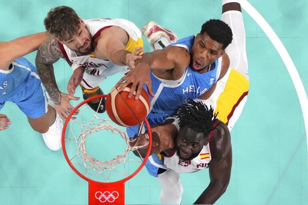 Giannis Antetokounmpo, center, of Greece, dunks as Juancho Hernangomez, of Spain, and Usman Garuba, left, of Spain, defend at the 2024 Summer Olympics, Tuesday, July 30, 2024, in Villeneuve-d'Ascq, France. (Evelyn Hockstein/Pool Photo via AP)