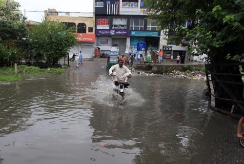 A motorcyclist drive through a flooded road caused by heavy rain in Peshawar, Pakistan, Tuesday, July 30, 2024. Heavy monsoons in northwest Pakistan triggered flash flooding, killing at least 14 people, 11 from the same family, officials said Tuesday. (AP Photo/Muhammad Sajjad)