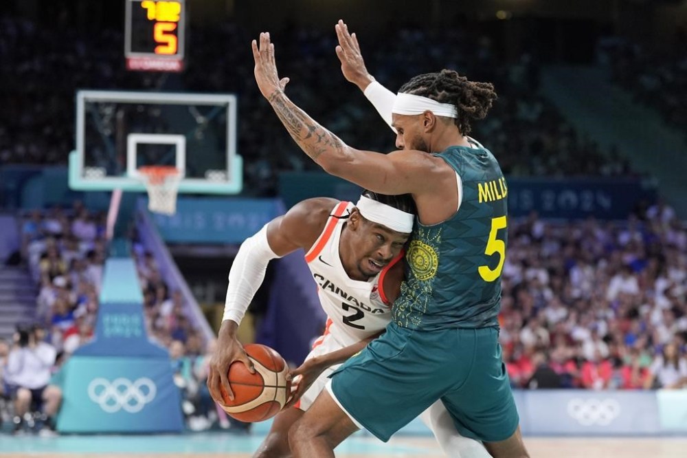 Canada's Shai Gilgeous-Alexander, left, tires to get by Australia's Patty Mills in a men's basketball game at the 2024 Summer Olympics, Tuesday, July 30, 2024, in Villeneuve-d'Ascq, France. THE CANADIAN PRESS/AP/Michael Conroy