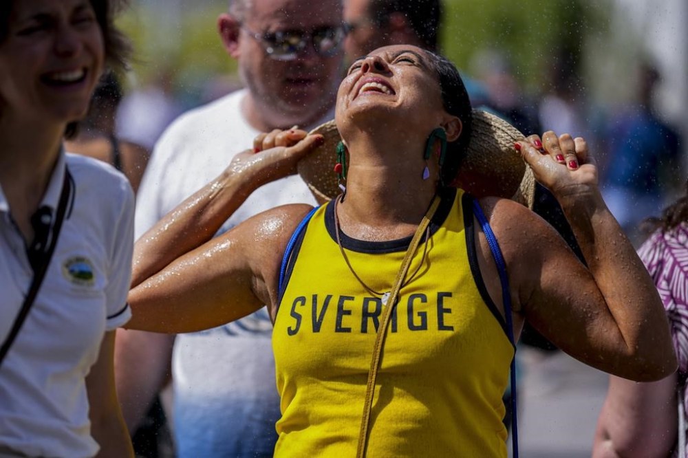 People cool off from a fountain at the Roland Garros stadium, at the 2024 Summer Olympics, Tuesday, July 30, 2024, in Paris, France. (AP Photo/Manu Fernandez)