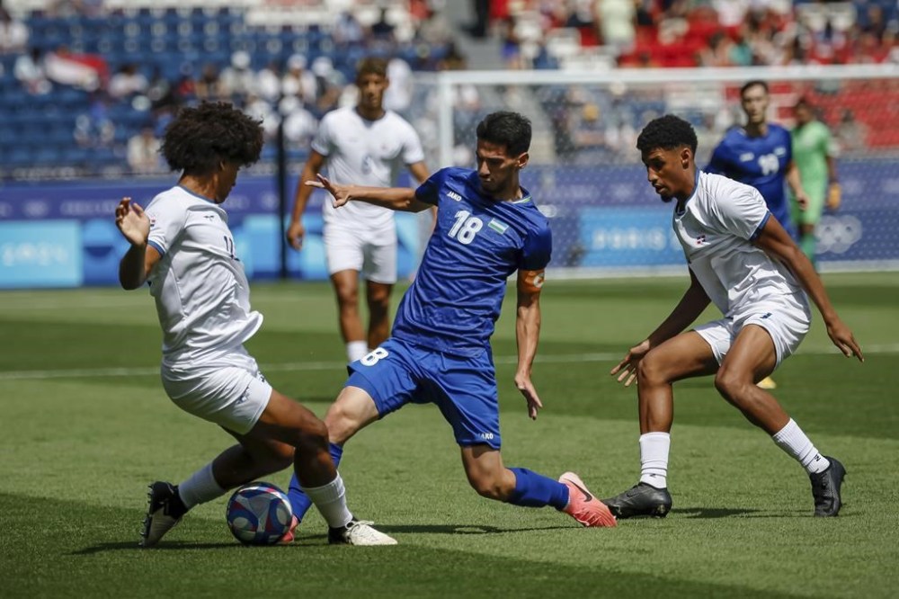 Dominican Republic's Gonzales Peter and Uzbekistan's Buriev Abdurauf compete for the ball during the men's group C match between Dominican Republic and Uzbekistan at the Parc des Princes during the 2024 Summer Olympics, Tuesday, July 30, 2024, in Paris, France. (AP Photo/Aurelien Morissard)