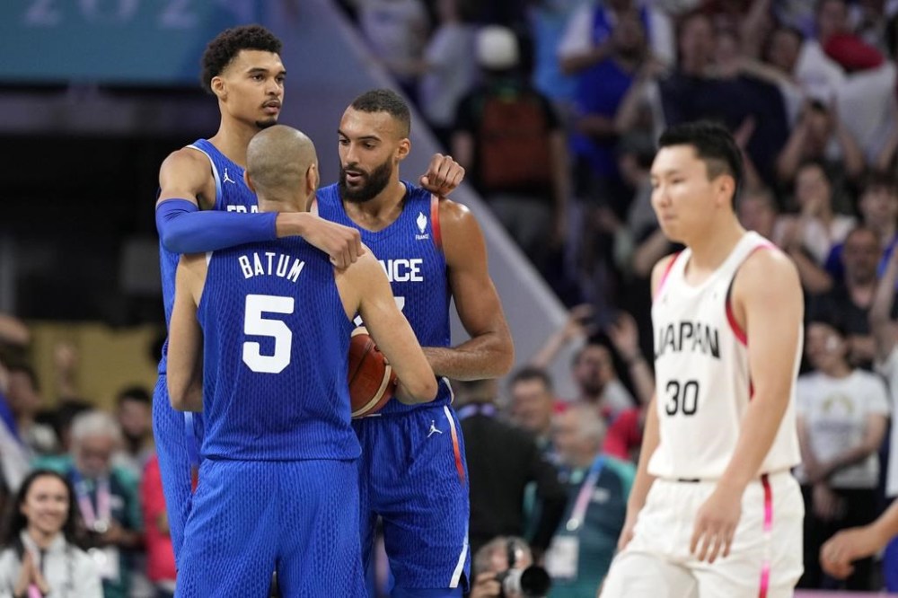 France's Victor Wembanyama, left, France's Nicolas Batum, second from left, and France's Rudy Gobert, second from right, as Japan's Keisei Tominaga walks away after France defeated Japan in a men's basketball game at the 2024 Summer Olympics, Tuesday, July 30, 2024, in Villeneuve-d'Ascq, France. (AP Photo/Michael Conroy)