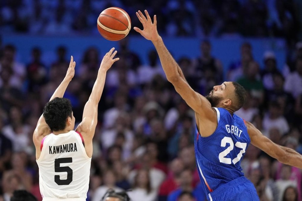 Japan's Yuki Kawamura, left, shoots as France's Rudy Gobert defends in a men's basketball game at the 2024 Summer Olympics, Tuesday, July 30, 2024, in Villeneuve-d'Ascq, France. (AP Photo/Michael Conroy)