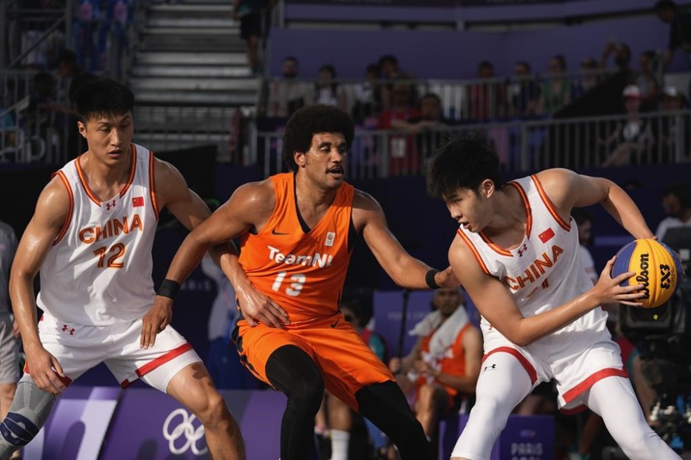 Zhao Jiaren of China, right, looks for an opening defended by Dimeo van der Horst of the Netherlands as Zhu Yuanbo of China looks to support, in the men's 3x3 basketball pool round match between China and the Netherlands at the 2024 Summer Olympics, Tuesday, July 30, 2024, in Paris, France. (AP Photo/Rebecca Blackwell)