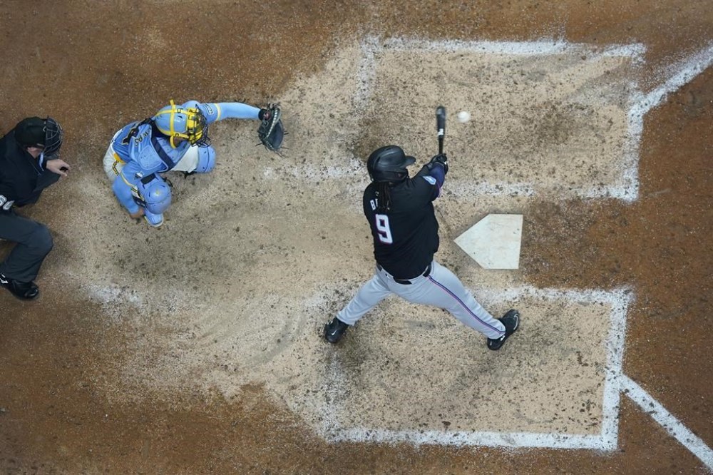 Miami Marlins' Josh Bell, right, hits a solo home run during the ninth inning of a baseball game against the Milwaukee Brewers, Friday, July 26, 2024, in Milwaukee. (AP Photo/Aaron Gash)
