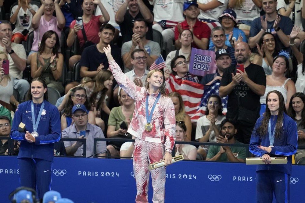 Canadians are showing a renewed interest in the Olympics thanks to a convenient time zone difference, diverse viewing options and more homegrown star power, observers say. Gold medallist Summer McIntosh, of Canada, waves as she stands on the podium with silver medallist Katie Grimes, left, and bronze medallist Weyant, both of the United States, after the women's 400-meter individual medley final at the 2024 Summer Olympics, Monday, July 29, 2024, in Nanterre, France. THE CANADIAN PRES/AP-Ashley Landis